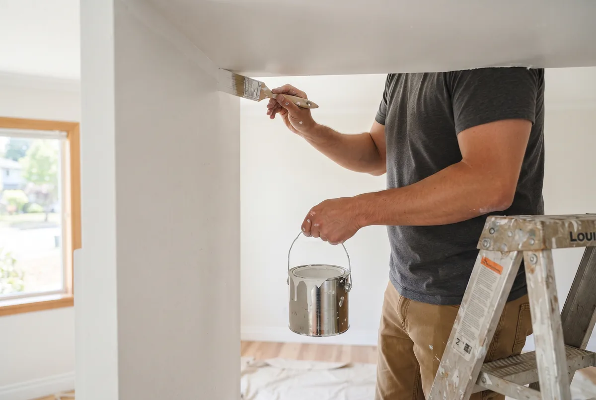 Hand cutting in a straight paint line where a wall meets the ceiling
